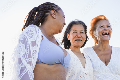 Happy multiracial senior women having fun together during summer beach vacation - Female friends with different body and ethnic concept