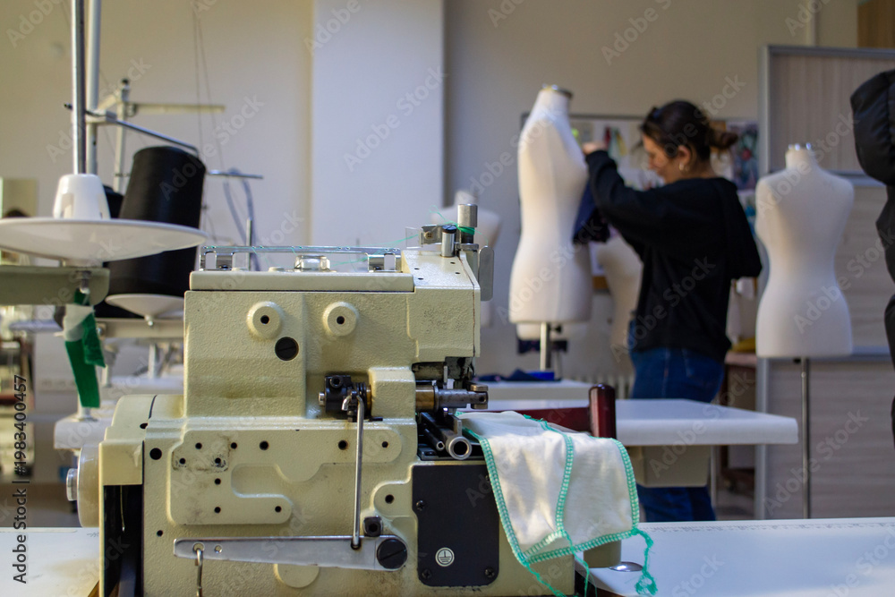 Naklejka premium Professional industrial overlock sewing machine in garment factory with designer in background
