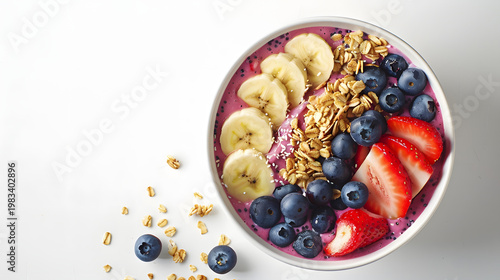 Delicious acai bowl with fresh strawberries, blueberries, banana slices, and granola on a white background