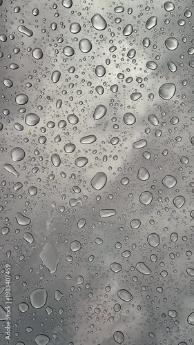 Raindrops dripping onto panoramic glass from above, close-up