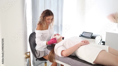 Skincare specialist distributes the clay mask thoroughly over the client's face, ensuring even coverage for a balanced complexion