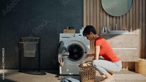 Fotografie Pretty girl sorting clothes putting laundry drum