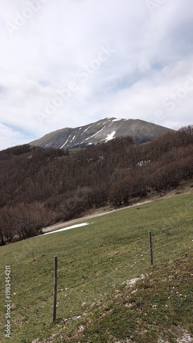 Vista da un sentiero di montagna, sotto un cielo coperto un paesaggio naturale maestoso.