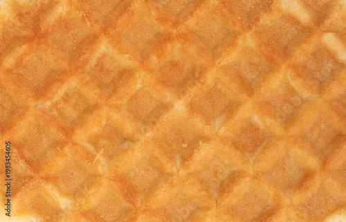 Waffle is shown close up. It shows a grid pattern and a golden brown color. No toppings or additions are visible. The surface is dry and crispy without any items placed on top.