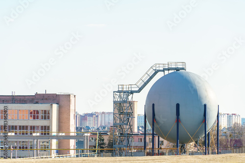 Spherical tank for storing dangerous chemicals, liquids and gases. A round barrel on the territory of a chemical plant.