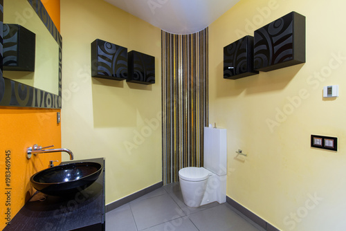 Modern bathroom interior design featuring yellow walls, bowl sink, and toilet