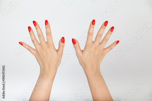 Quadro su tela Two female hands with vibrant red manicure isolated on white background professi