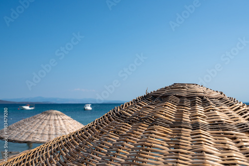 Woven Straw Sun Umbrellas On A Tropical Beach Background