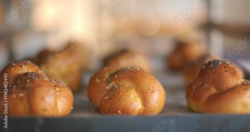 Lens shifting focus and exposure, bringing front braided roll sharp on tray, showing seeded crust