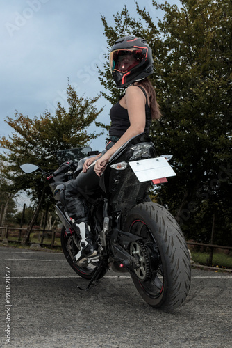 Woman biker wearing helmet riding motorcycle enjoying freedom