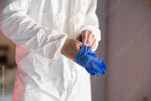 Billede på lærred Professional preparing for work, wearing protective hazmat suit and blue medical