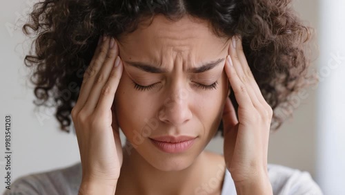 Woman presses her temples in pain, illustrating stress, headache, and elevated cortisol affecting mental and physical wellbeing.