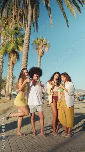 Group of diverse friends having fun, drinking mojitos and celebrating summer on a tropical beach