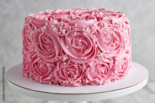 Beautiful Cake Decorated With Pink Frosting Roses and White Sprinkles on a Wh...