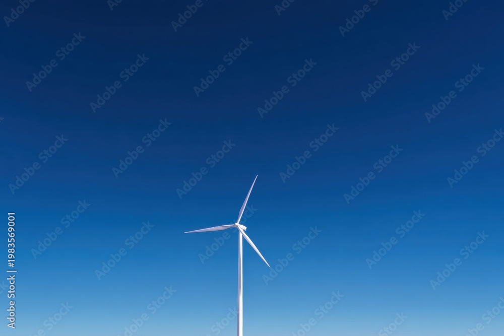 Fototapeta premium Wind turbine generating clean renewable energy against blue sky