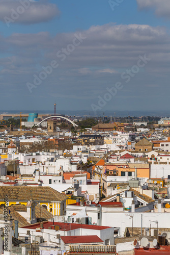 Seville, Andalusia, Spain, panoramic rooftop view showcasing the historic city center's traditional architecture and the modern structures of La Cartuja island, including Isla Mágica amusement park an