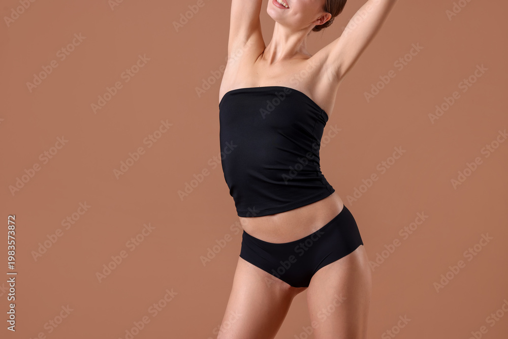 Obraz premium Smiling woman in underwear with slim body on beige background, closeup. Space for text