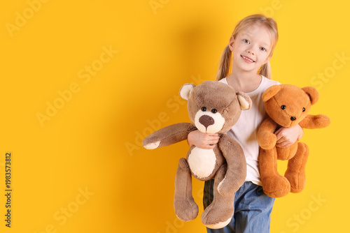 Tableau sur toile Little girl with her teddy bears on yellow background