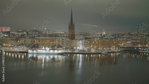 A stunning view of a city skyline illuminated at night, showcasing buildings and a river reflecting lights.