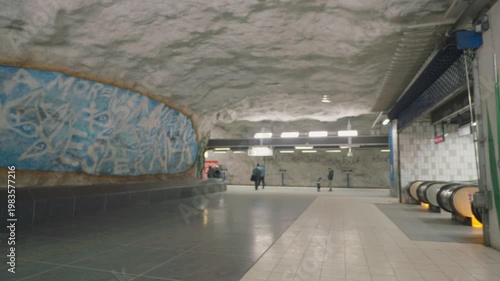 An intriguing view of an underground station featuring a unique textured wall and escalators, creating a captivating atmosphere for travelers.