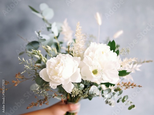 Elegant White Flower Bouquet Held Against a Soft Background During Sunny Dayl...