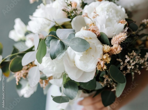 Bridal Bouquet Features White Flowers and Green Leaves Held by Bride in a Wed...