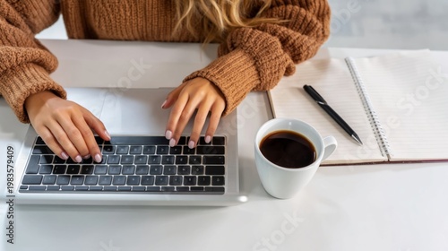 Person Types on Laptop While Sitting at Desk With Coffee and Notebook During ...