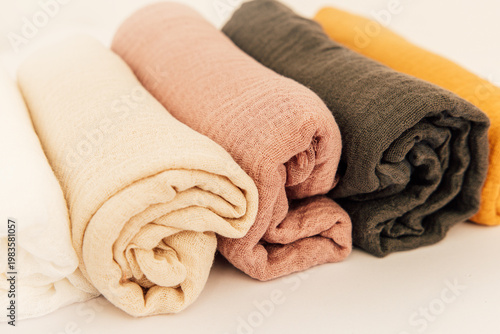 Soft and colorful rolled fabrics arranged neatly on a plain background for display and inspiration
