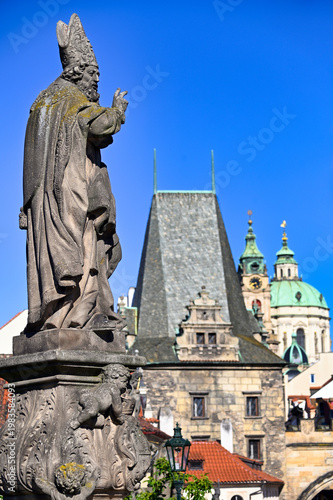 Statue of Saint Adalbert on Charles Bridge with St. Nicholas Church Background, Prague