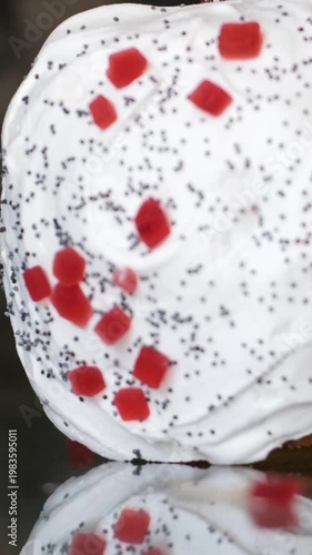 Easter kulich with poppy seeds white icing and red candied fruits falling on top festive sweet bread slow motion bakery