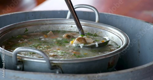Vietnamese hot pot soup with rice carrots and sea fish pieces simmering in metal pot on table showing traditional shared cooking process