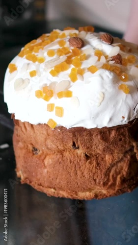 Slicing Easter kulich with candied fruit and almond icing soft sweet bread cutting with knife festive bakery close-up