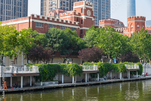 A striking view of Tianjin's waterfront, showcasing a blend of historic red-brick architecture and towering modern skyscrapers along the river. China 22 May 2025