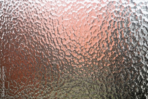 Foto Abstraktes Motiv mit Glasmusterwand vor rot-grau-pinkem Hintergrund mit Licht