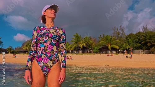 A beautiful girl in a swimsuit stands in the crystal clear water of a warm ocean and a feeling of freedom