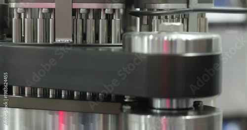 Close up of rotating multi head mechanism with metal pins moving in circular motion. Automated industrial system for precise processing, filling or assembly in modern factory environment.