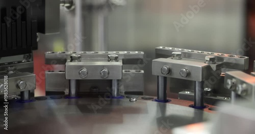 Close up of rotating multi head mechanism with metal pins moving in circular motion. Automated industrial system for precise processing, filling or assembly in modern factory environment.