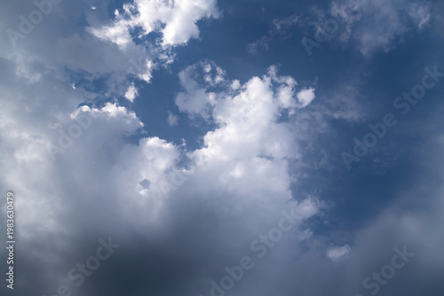 Dramatic cumulus clouds gather over a deep blue sky, contrasting bright white...