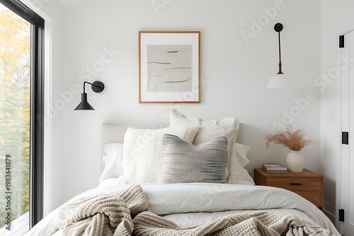 Minimalist bedroom with neutral bedding, framed and warm lighting