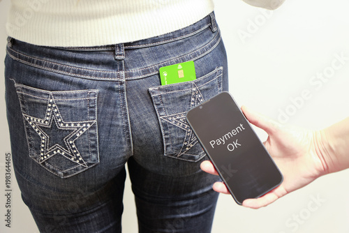 A person with their back to the camera, wearing tight jeans, has a bank card partially protruding from one of their pockets, leaving it visible and vulnerable. This is a risky situation where someone 