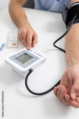 Person pressing digital blood pressure monitor button during home health check
