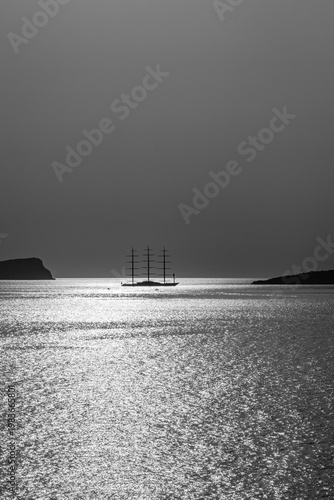 Beautiful view of a three masts sailing ship next to the volcano Palea Kameni in Santorini Greece in black and white