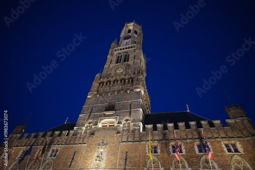 Der Turm des Belfried oder Belfort vor blauem Himmel im Licht der Dämmerung am Abend am Grote Markt als Teil des Unesco Weltkulturerbe in den Gassen der Altstadt von Brügge in Westflandern