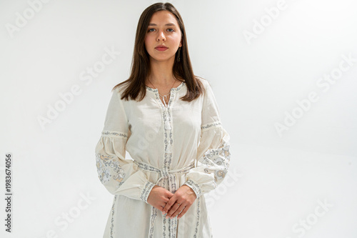 Portrait of a young Ukrainian woman in a traditional white embroidered dress, vyshyvanka. Isolated on white background in studio. Ethnic fashion and heritage concept