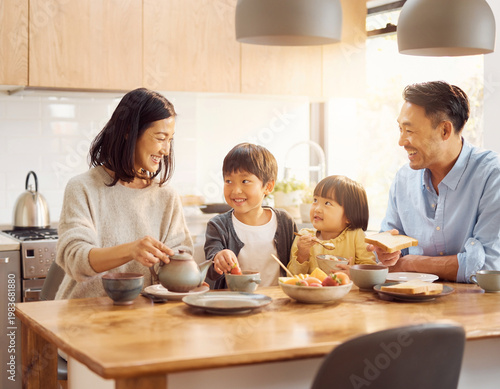 明るいキッチンで朝食を食べる幸せな日本人家族