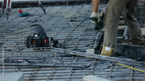 Workers using a grinder at a construction site. Work process at a construction site. Construction of an industrial building from the inside.