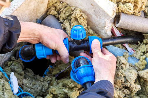 Compression tee fitting for HDPE pipes in hands of plumber.