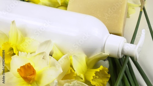 A bar of soap and a bottle of shower gel, fresh flowers daffodil are on a white background, cosmetics based on daffodils