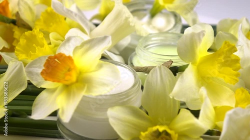 Jars with face cream, facial mask, fresh flowers daffodil are on a white background, cosmetics based on daffodils, slow motion