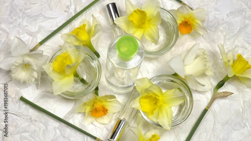 Bottle with face lotion, daffodil extract, fresh flowers daffodil are on a white background, cosmetics based on daffodils